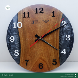 Bring timeless style to your space with "Cael", a 12-inch round wall clock that blends elegant design with industrial charm. Handcrafted using a unique combination of wood, resin, and acrylic, this statement piece adds depth, character, and modern sophistication to any room.

Perfect for home interiors, office walls, or business spaces, Cael doesn’t just tell time — it tells your story. With options for custom engraving or logo placement, it also makes a standout choice for corporate gifts, housewarming pre