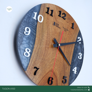Bring timeless style to your space with "Cael", a 12-inch round wall clock that blends elegant design with industrial charm. Handcrafted using a unique combination of wood, resin, and acrylic, this statement piece adds depth, character, and modern sophistication to any room.

Perfect for home interiors, office walls, or business spaces, Cael doesn’t just tell time — it tells your story. With options for custom engraving or logo placement, it also makes a standout choice for corporate gifts, housewarming pre